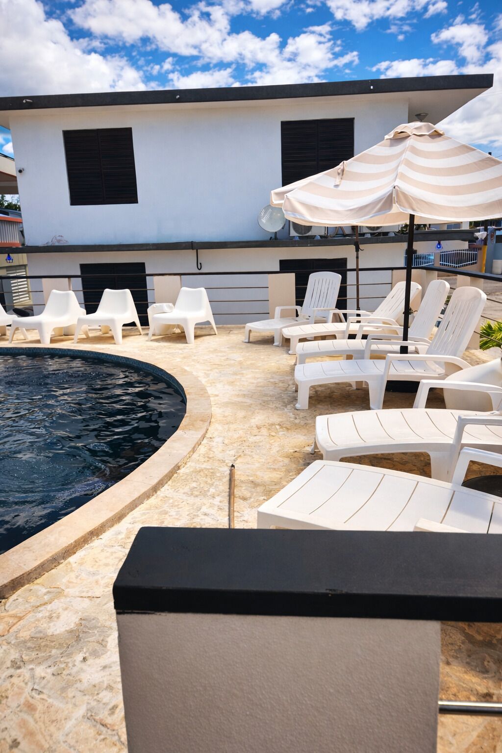 Un espace piscine avec des chaises longues et un parasol à rayures.