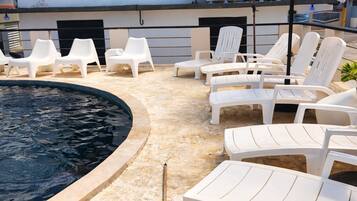 Un espace piscine avec des chaises longues et un parasol à rayures.