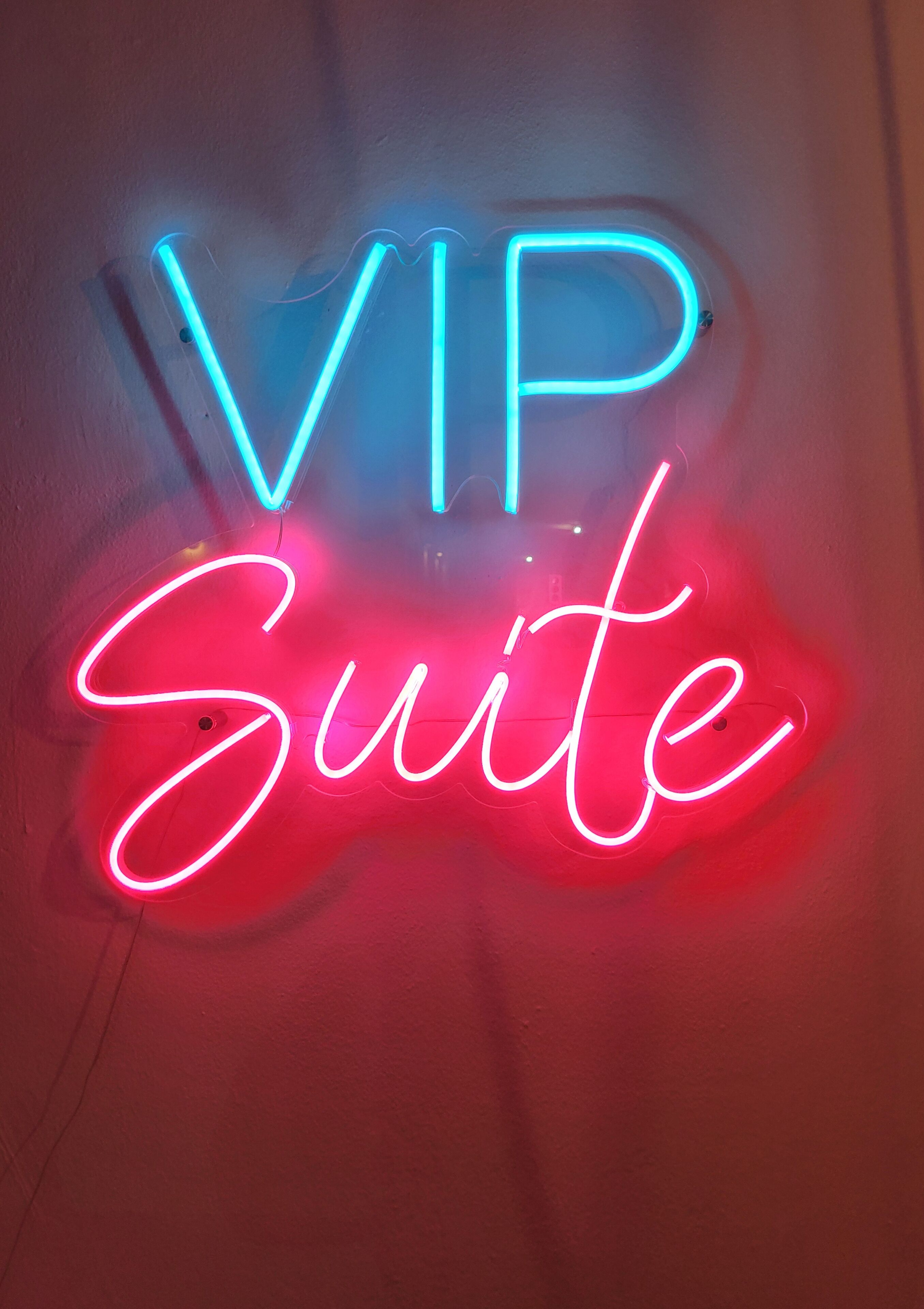 Ein Neon-Schild mit der Aufschrift 'VIP Suite' in Blau und Rot.