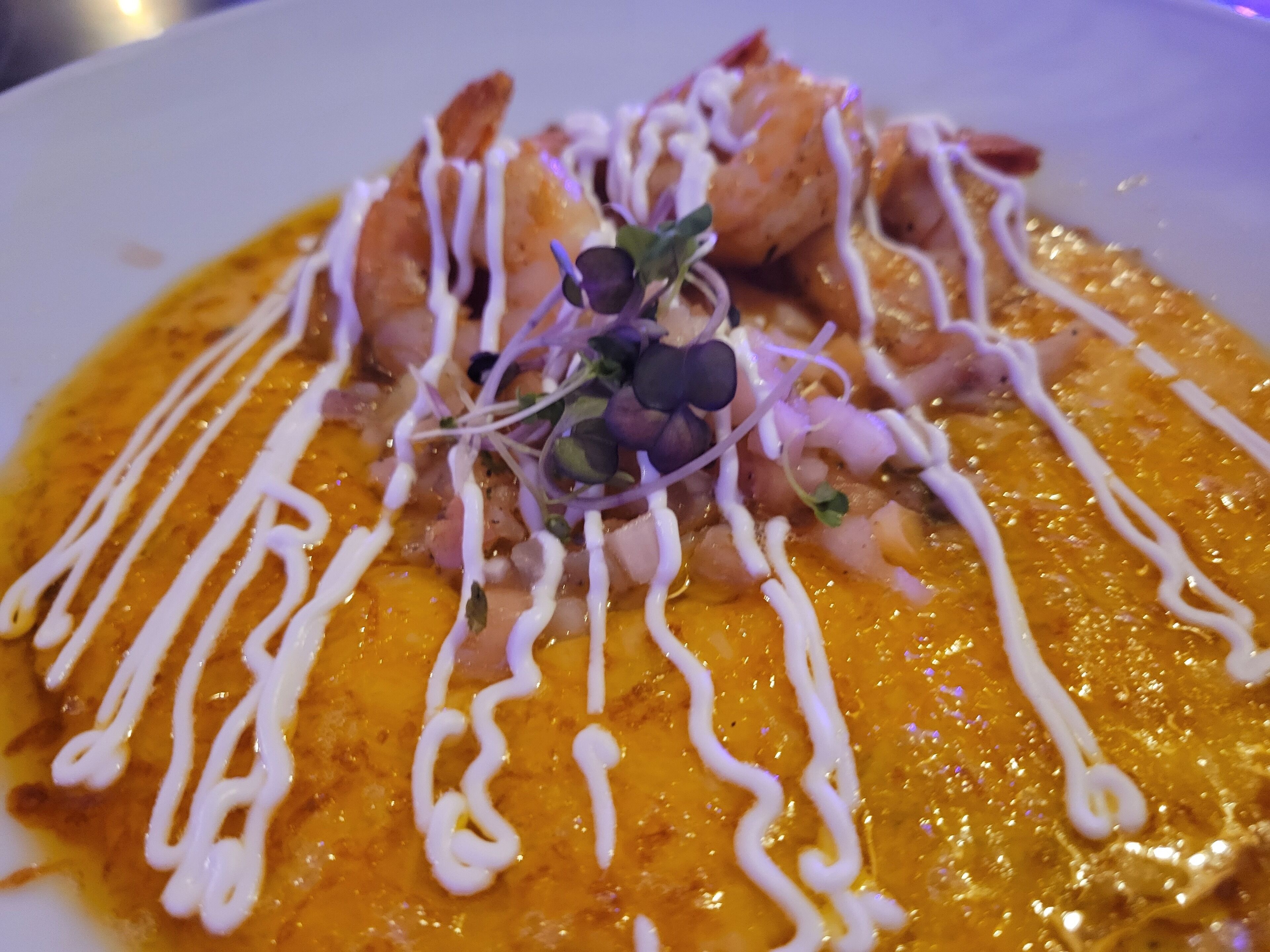 A plate of food with shrimp, sprouts, and a creamy sauce.