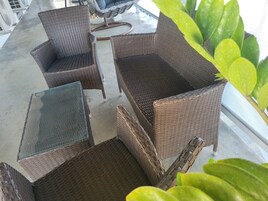Un comedor con sillas de mimbre y una mesa de vidrio.