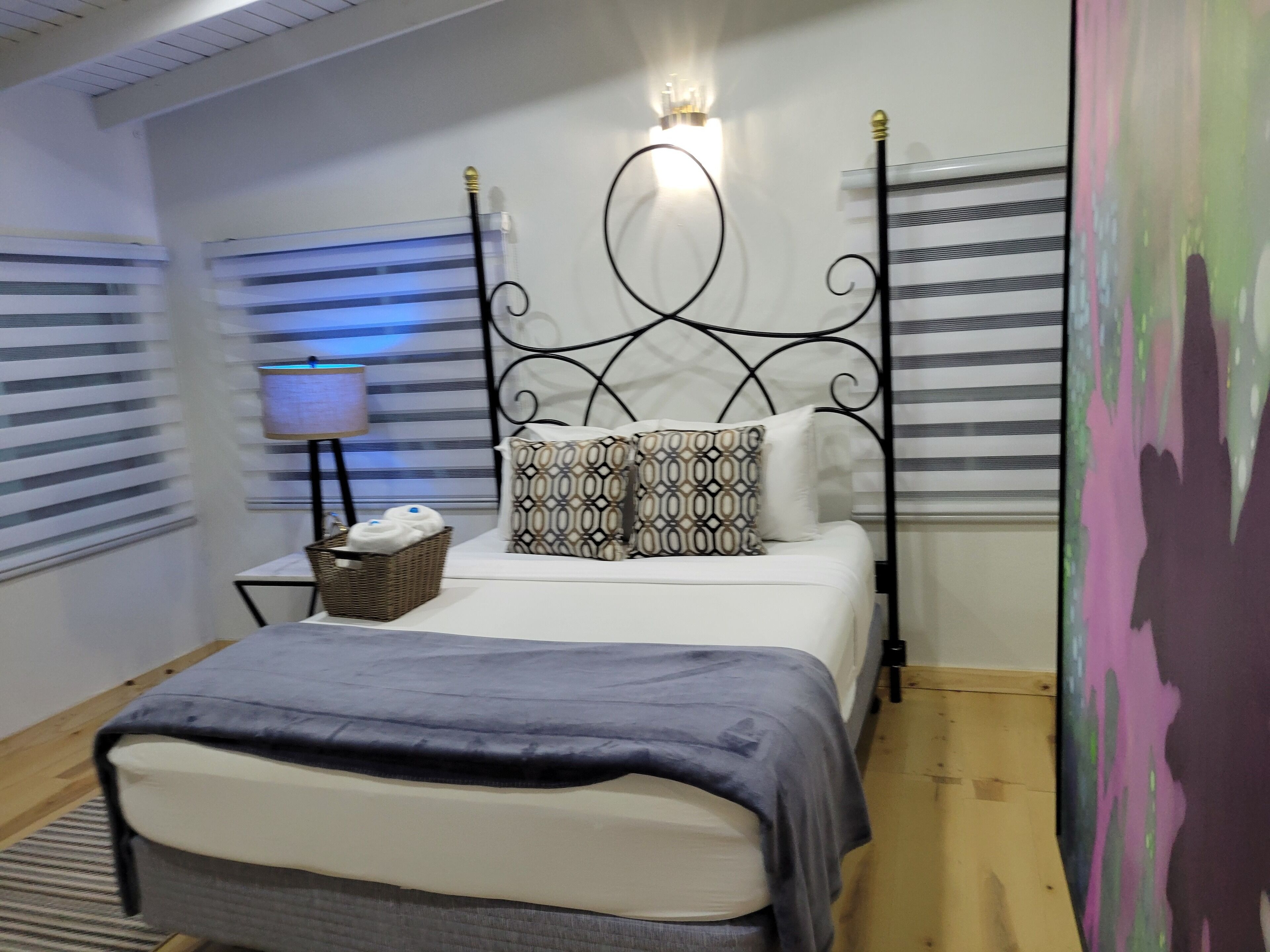 A neatly arranged bedroom with a bed, a bedside table with a lamp, and a wall-mounted light fixture.