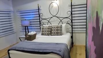 A neatly arranged bedroom with a bed, a bedside table with a lamp, and a wall-mounted light fixture.