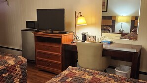 A hotel room with two beds, a desk with a computer, a lamp, a coffee maker, and a trash bin. - Cortland Motel (Cortland)
