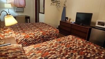 Quarto de hotel com duas camas, televisão, cômoda e micro-ondas.
