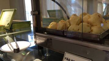 A display case with pão de queijo and a sign indicating it's a cheese bread.