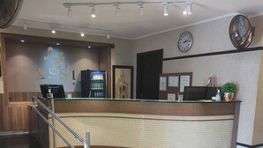 Un espace d’accueil comprenant un comptoir, une horloge et un distributeur automatique.