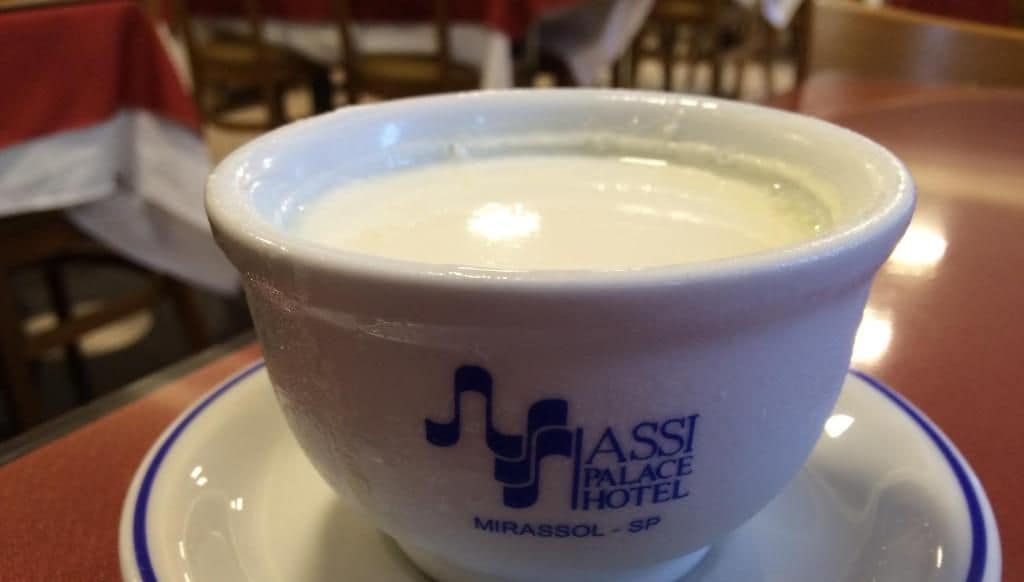 Eine weiße Tasse mit blauem Rand und Logo, auf einem Untertasse platziert.