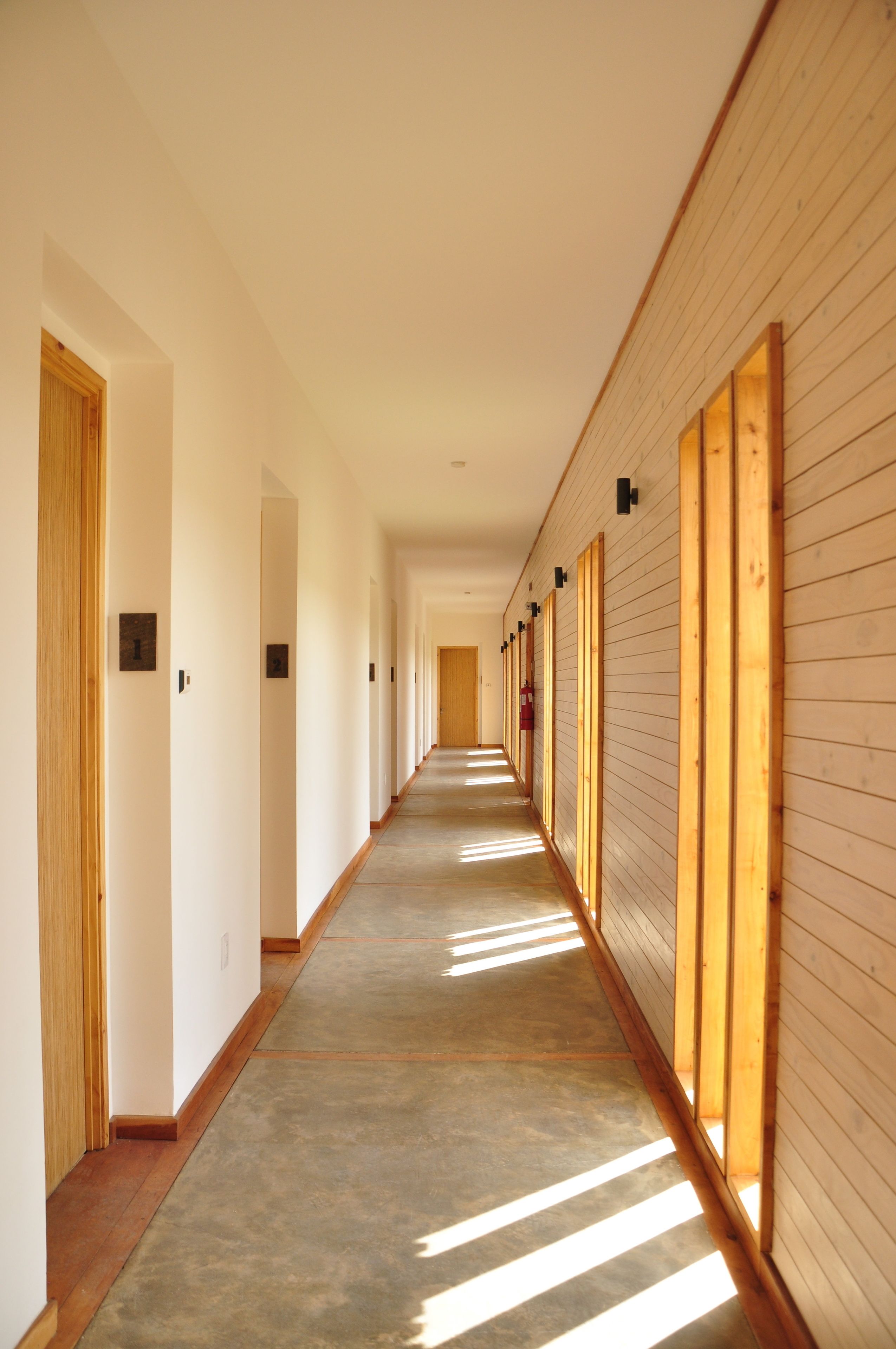 A long, narrow hallway with wooden paneling on one side and a plain wall on the other.