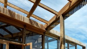 A wooden interior with large windows offering a view of the sea. - Hotel Simple Patagonia (Natales)