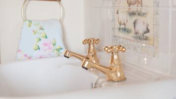 Ein Badezimmer mit goldenem Wasserhahn, einem Blumendekor-Handtuch und einer Wand mit Tierdarstellungen.