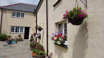 A building with multiple windows, some with hanging flower baskets, and a stone-paved courtyard.