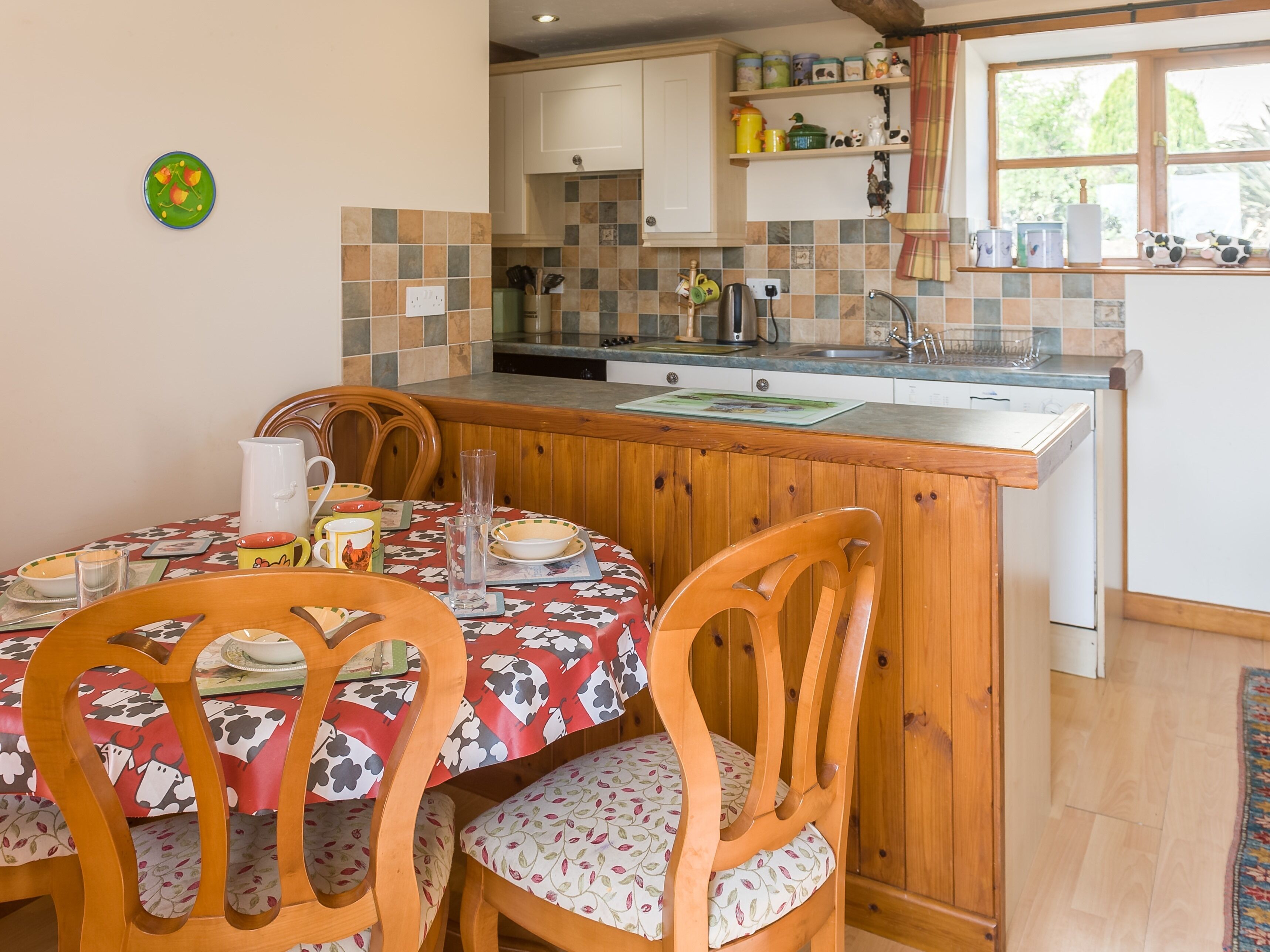 Una cocina con una isla de madera, una mesa de comedor con sillas y una ventana con cortinas.