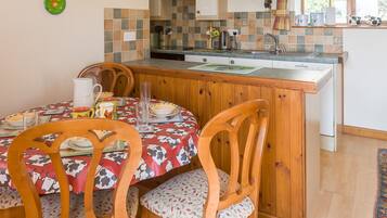 Una cocina con una isla de madera, una mesa de comedor con sillas y una ventana con cortinas.