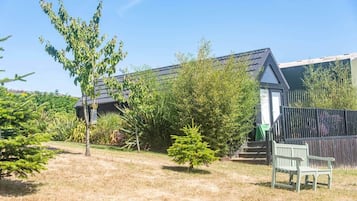 Ein Wohnhaus mit einem umzäunten Garten und einer Bank.