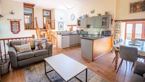 A spacious living area with a sofa, coffee table, and dining table. A kitchen with modern appliances and a small island is visible.