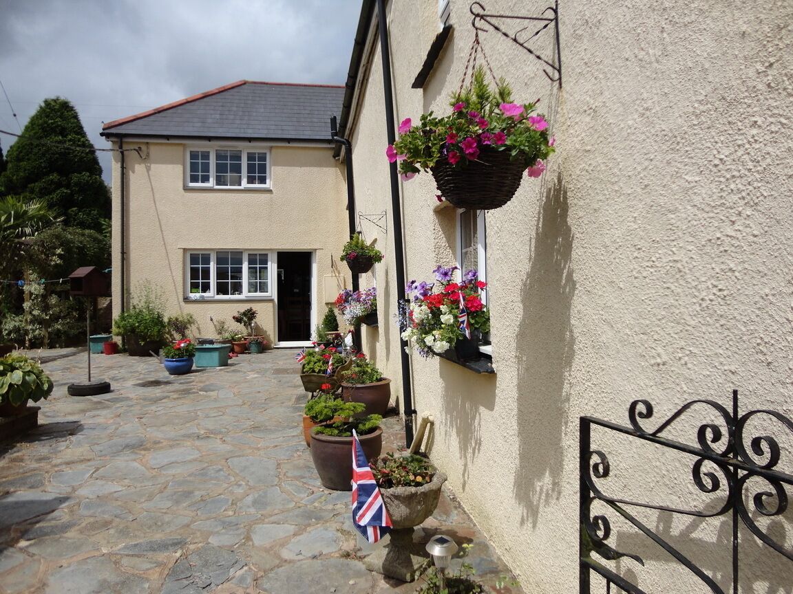 A stone-paved courtyard with hanging flower baskets and a flag.