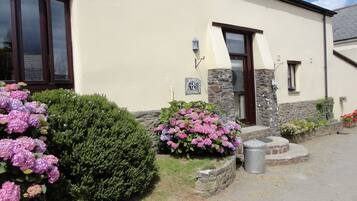 A building with a stone facade, a wooden door, and a sign reading "FRANK COTTAGE."