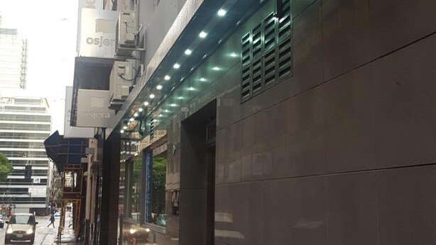 Un edificio con fachada de baldosas, unidades de aire acondicionado y una serie de luces a lo largo de la planta baja.