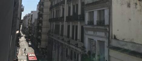 A narrow street lined with multi-story buildings, some with balconies and decorative facades.