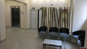 Un área de espera con mostrador de recepción, dos sofás, una mesa de centro y un cartel en la pared.