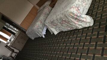 A room with a patterned carpet, a bed with floral bedding, and a brick wall.