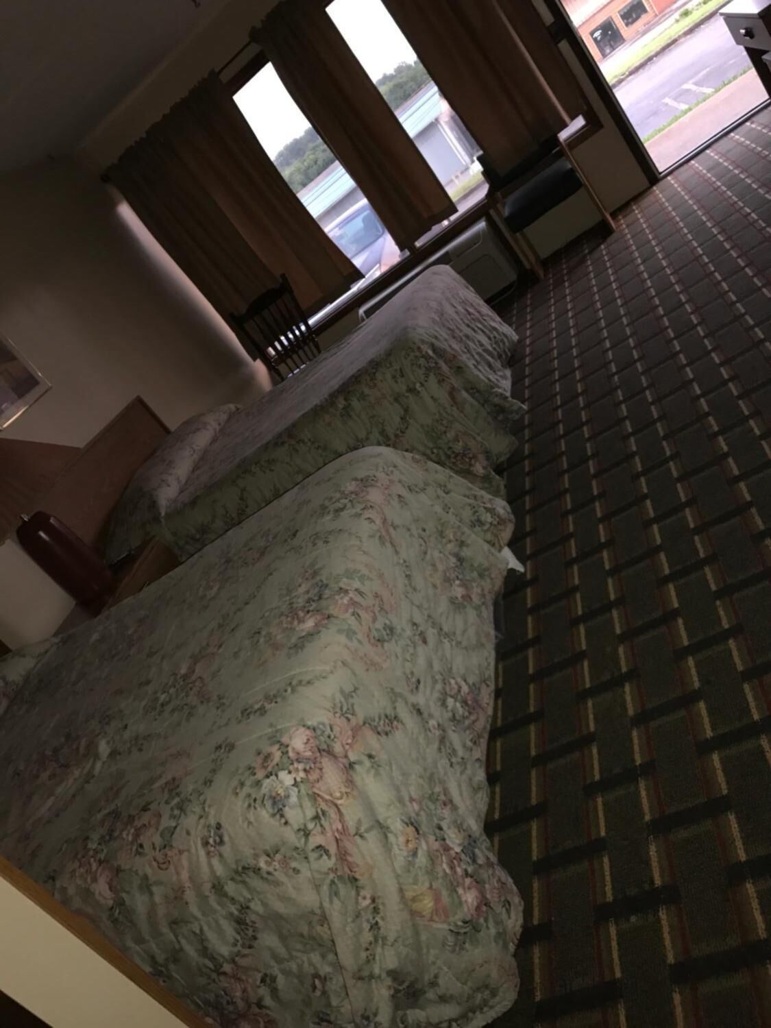 Una habitación de hotel con una cama, una silla, un ventanal y vista a la calle.