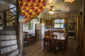 A kitchen with a stone staircase, wooden dining table, and chairs. - Casa Esperanto (Salango)
