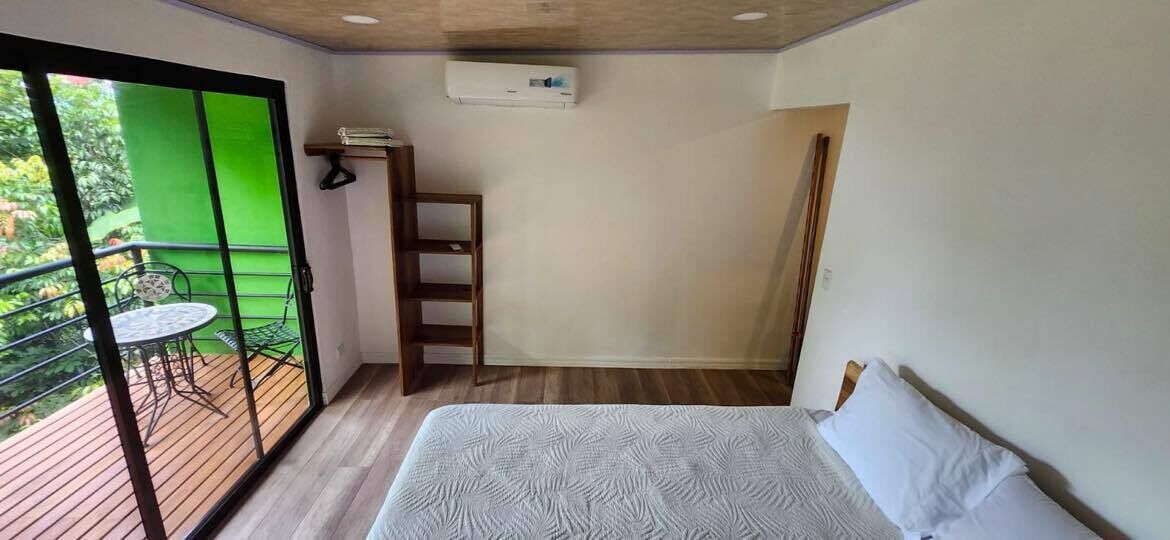 Un dormitorio con cama, una escalera, una mesita y un balcón con una silla.