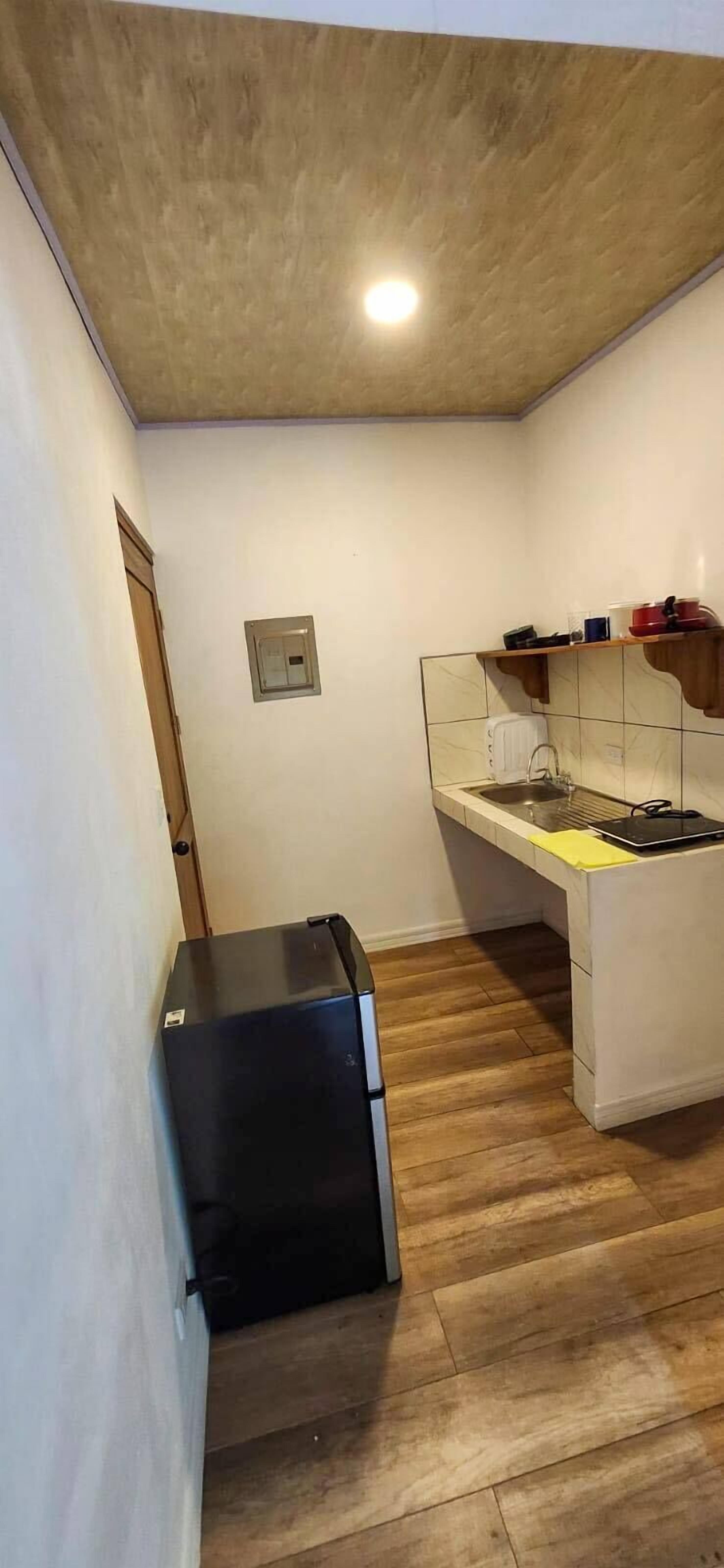 A compact kitchen with a built-in stove, a small refrigerator, and a tiled backsplash.