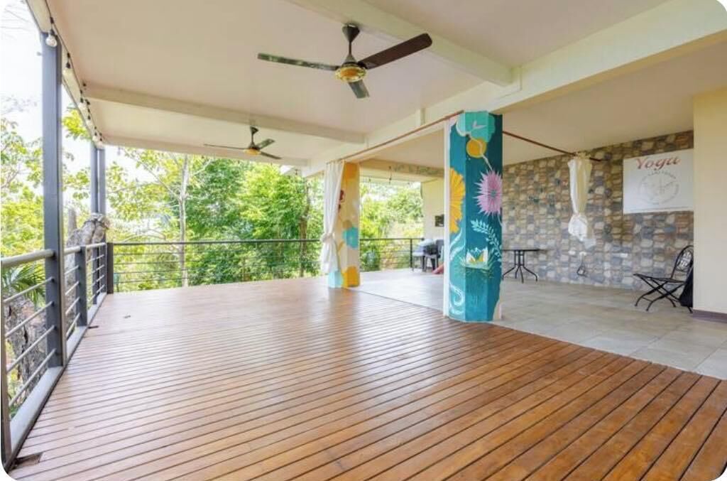 A covered outdoor area with a wooden deck, ceiling fans, and a yoga sign on the wall.