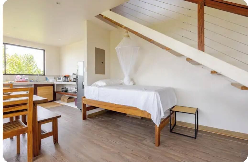 A bedroom with a bed, wooden furniture, a small table, and a window with a view.