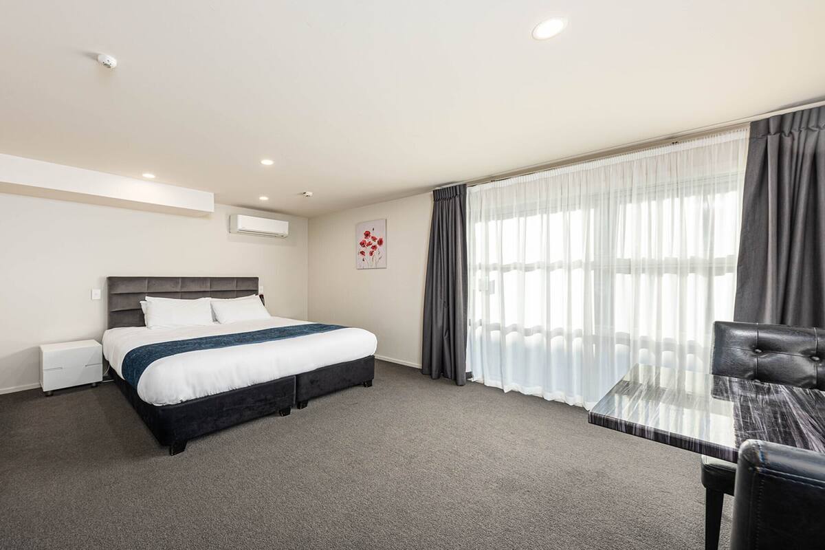 A hotel room with a bed, a desk, and a chair.