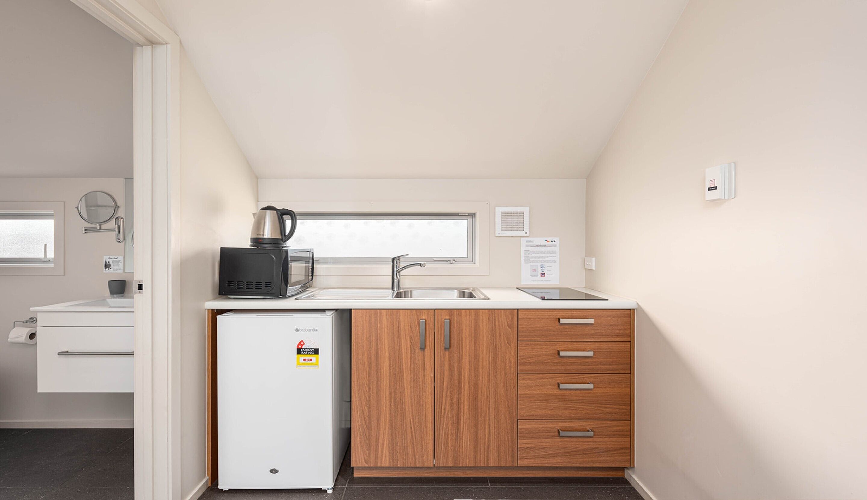 A compact kitchen with a refrigerator, microwave, and sink.