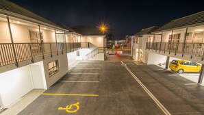 Ein Parkplatz mit Stellplätzen für Menschen mit Behinderung, ein gelber Wagen und Gebäude mit Balkonen.