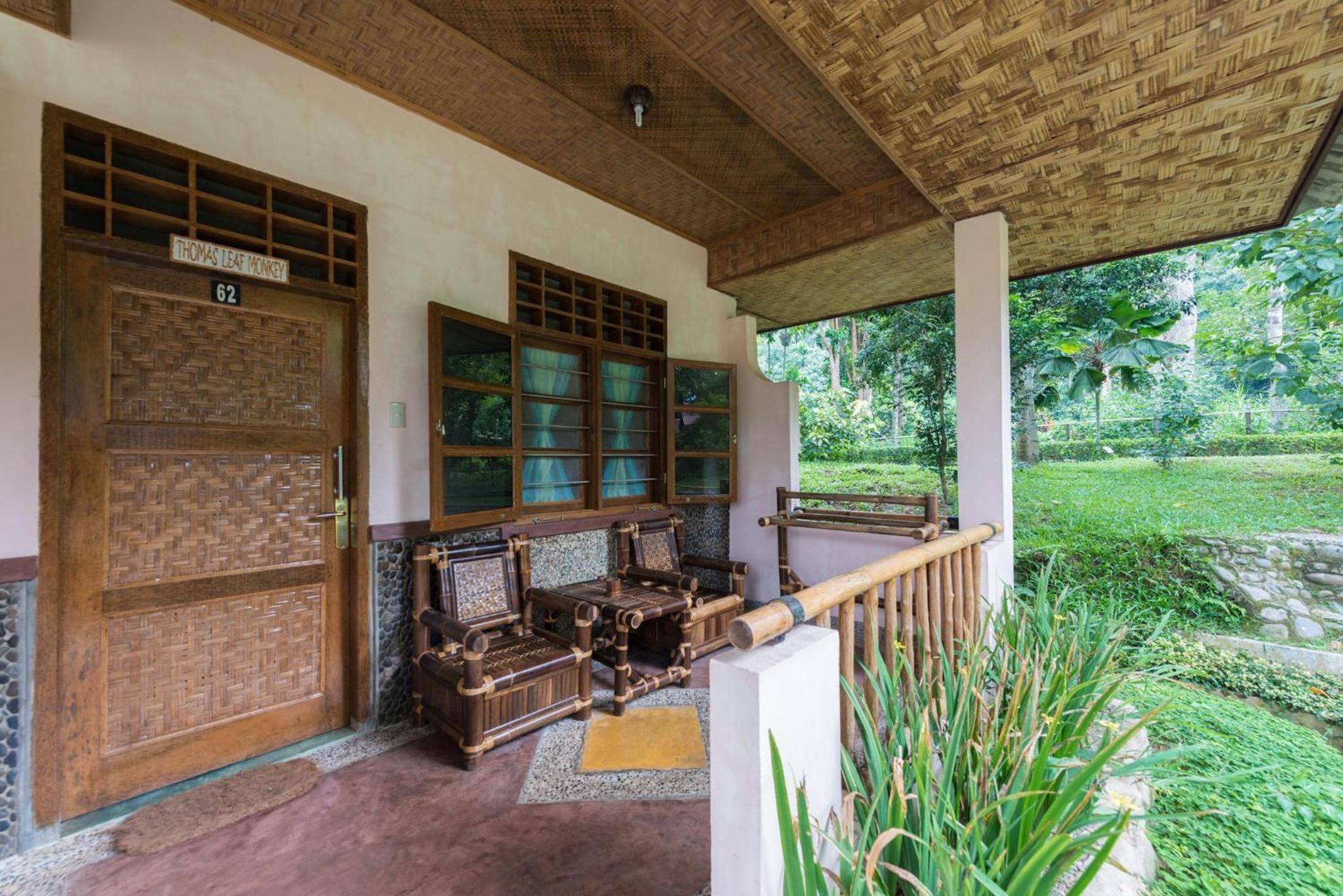 A traditional wooden door with a sign, a covered porch with a bench, and a view of a lush garden.