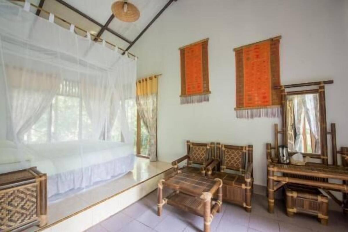 Een kamer met een bed, twee stoelen, een tafel en een spiegel.