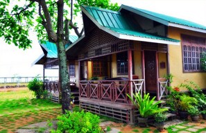 A traditional wooden house with a green roof, a porch, and potted plants. - Pems Pension and Restaurant (Taytay)