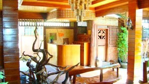 A reception area with a wooden reception desk, a chandelier, and a decorative tree sculpture.
