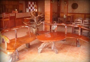 A restaurant with a unique wooden bench design, a tiled floor, and a traditional decor style. - Pems Pension and Restaurant (Taytay)