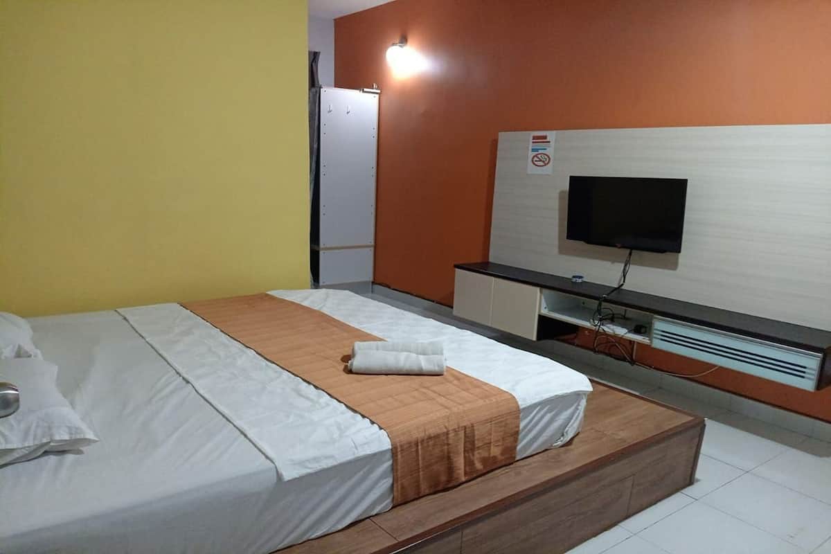 A hotel room with a bed, a TV, a desk, and a wardrobe.