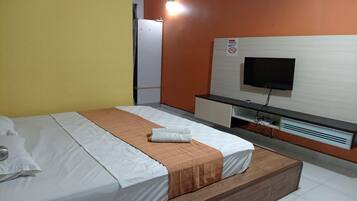 A hotel room with a bed, a television, a desk, and a cabinet.