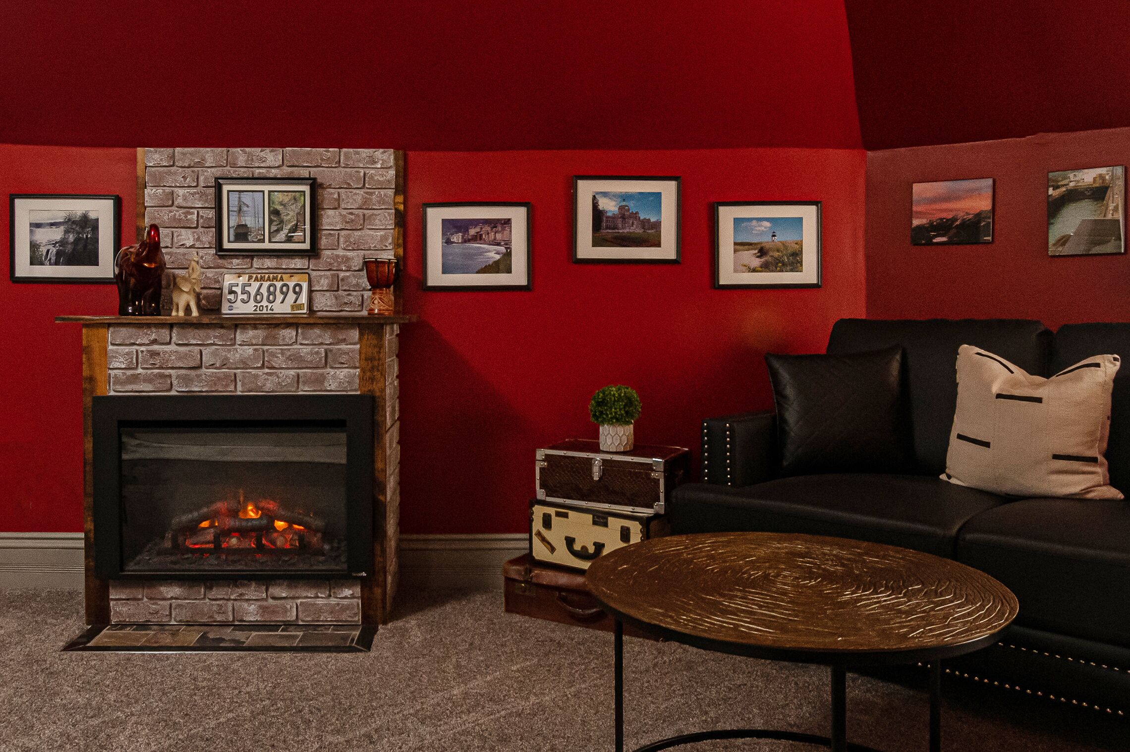 Una sala de estar acogedora con chimenea, un sofá de cuero negro y una mesa de centro.