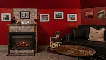 Una sala de estar acogedora con chimenea, un sofá de cuero negro y una mesa de centro.