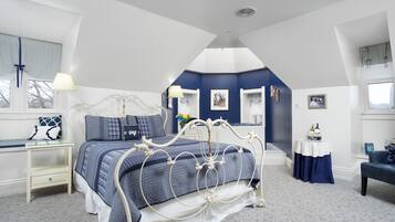A bedroom with a bed, a nightstand, a dresser, a window, and a small table with a lamp.