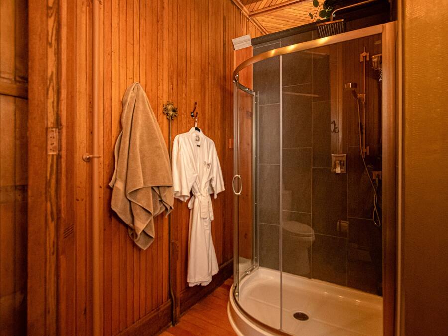 A wooden interior with a glass-enclosed shower and a bathtub.