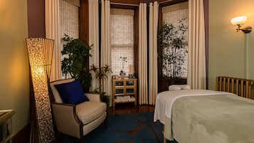 Une chambre d’hôtel avec un lit, une chaise, une lampe sur pied et une petite table sur laquelle est posée une plante.