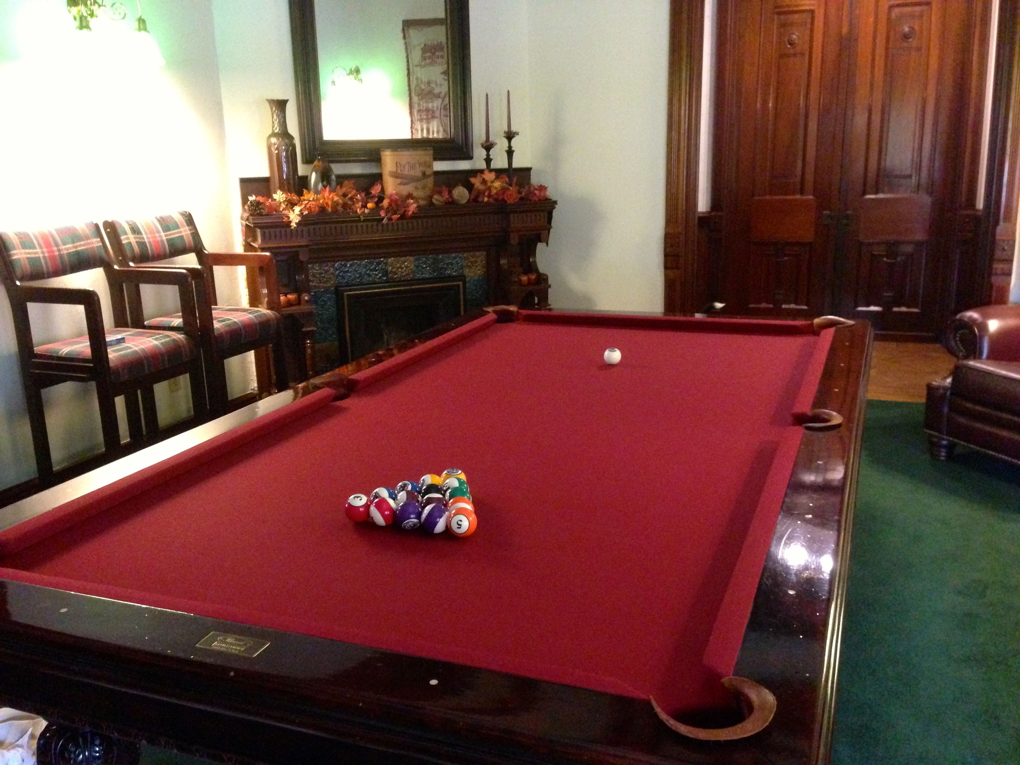 Une table de billard avec des billes, une cheminée et un miroir.