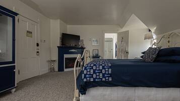 A bedroom with a large bed, a fireplace, a television, and a wardrobe.