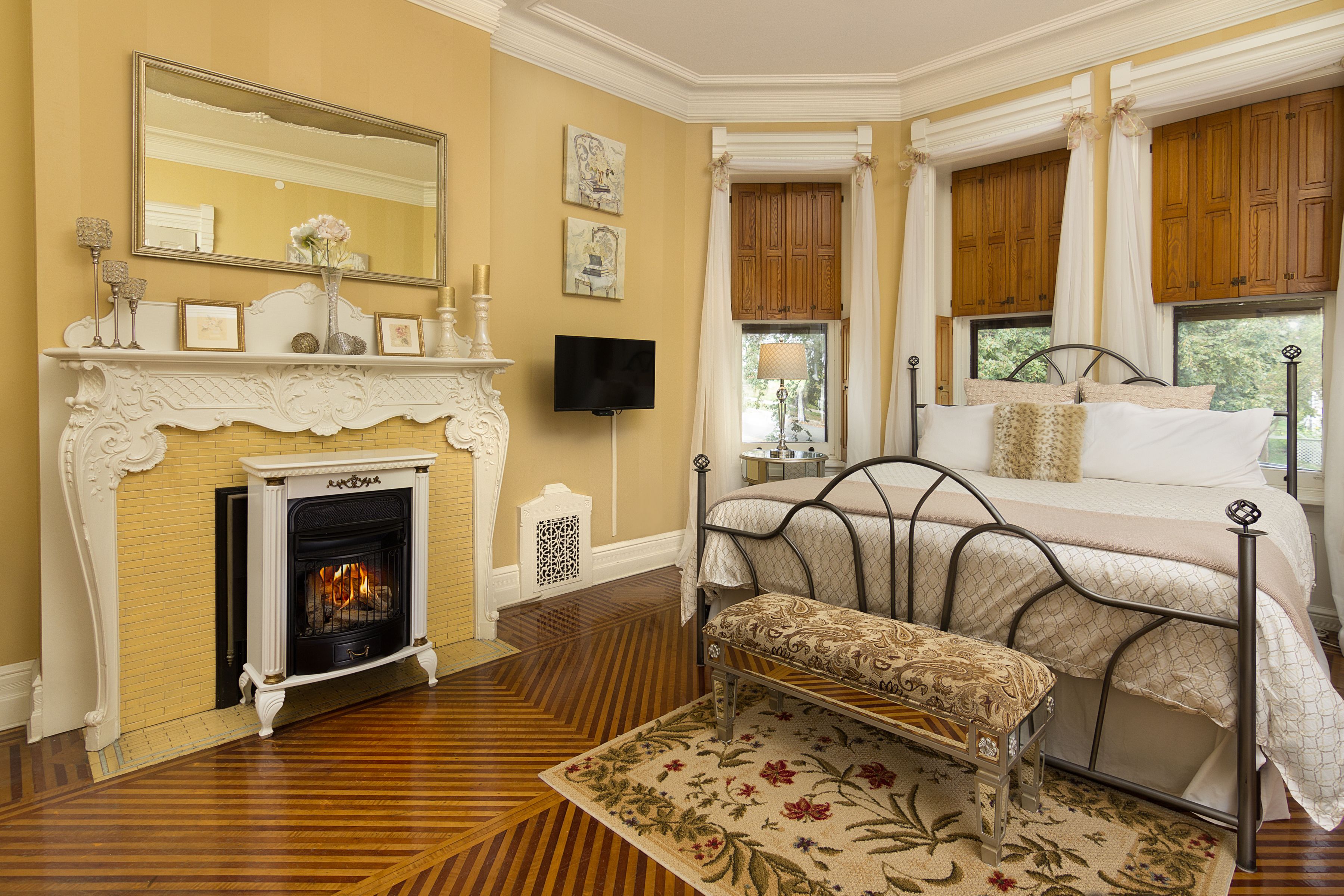 A bedroom with a fireplace, a bed with a canopy, and a television.
